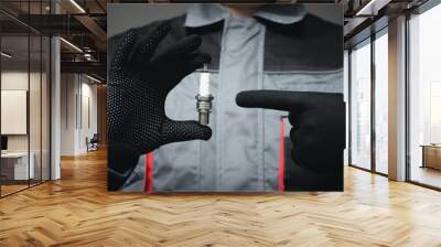 Car engineer is showing a new car spark plug close up. Wall mural