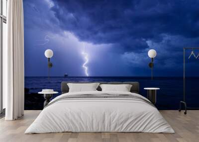 A storm front with rain and curved lightning striking the sea near an abandoned marine science platform Wall mural