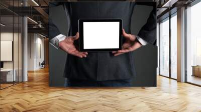 Digital tablet computer with a blank screen in a business man hands behind his back on gray background. Special offer mock up. Business proposal template. Wall mural