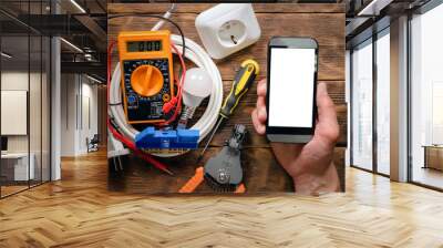 Electrician call template. Electric equipment and mobile phone with blank screen in hand close up. Wall mural