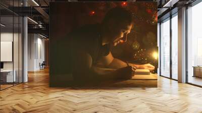 Person writes a letter to a Santa Claus under a Christmas tree branches at night. Student man is studying in Christmas holidays. Wall mural