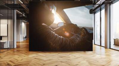 Rally car driver sitting by the steering wheel in the sunset rays concept. Wall mural