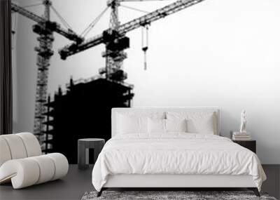 silhouettes of two elevating cranes on background of buildings Wall mural