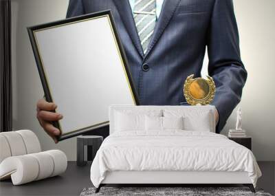 Top manager award mockup. Best office employee award. Business man holding empty blank photo frame (gratitude letter) in one hand and gold medal in another one. Gratitude concept. Grateful letter. Wall mural