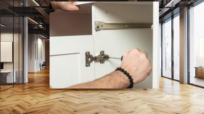 a male furniture assembler is engaged in assembling a desk with a bedside table Wall mural