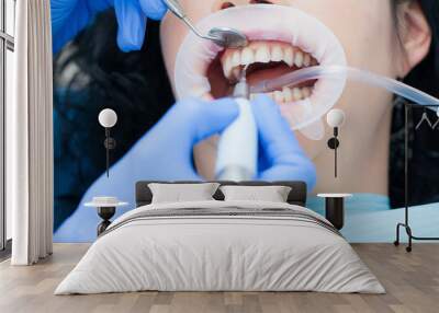 A woman in the dental hygienic and dental clinic professional teeth whitening and ultrasonic cleaning. Odontics and health of the mouth. Wall mural