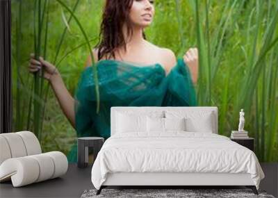 a young woman is standing on a swamp, covered by a green cloth Wall mural