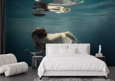 Girl in a dress with ribbons swims underwater Wall mural