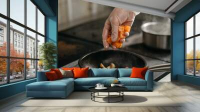 hand in glove throws chopped salmon on a heated pan with mushrooms Wall mural