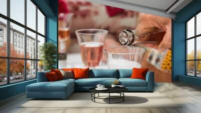 hand of an elderly man pours pink wine into glass glasses. Wall mural