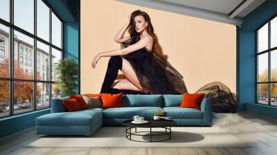 Sensual brunette woman is sitting posing in provocative sexy black wedding dress transparent cloth and high boots Wall mural