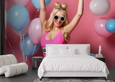 Trendy cheerful blonde woman on birthday party having fun with pastel color air balloons  Wall mural