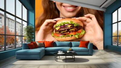 Woman eat burger sandwich with hungry mouth on yellow background Wall mural