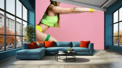 Woman exercising doing postnatal workout. Female fitness instructor working out with a rubber resistance band on modern pink Wall mural