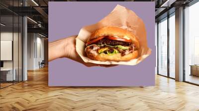 Woman hands hold big cheese burger barbeque sandwich with marble beef on purple Wall mural