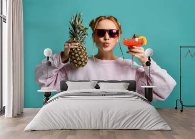 Young woman in fashion sunglasses hold or offer tropical margarita cocktail strawberry and pineapple Wall mural