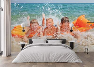 Three kids having fun splashing water on a beach Wall mural