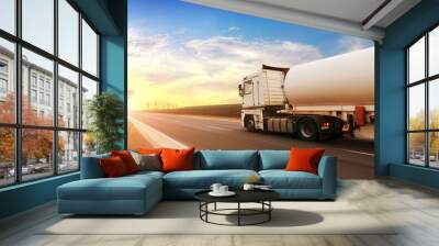 A fuel tanker truck shipping fuel on the countryside road in motion against a sky with a sunset Wall mural