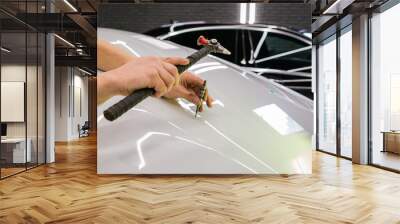 A specialist repairs a dent on the car body without painting. PDR. Process of paintless dent repair on car body. The mechanic at the auto shop with tools to repair dents in car body. Body repair. Wall mural