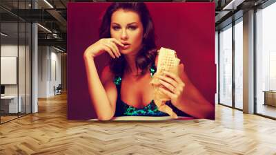 Sexy woman sitting at table in night club or bar and eating kebab or shaverma. Fashion style portrait Wall mural