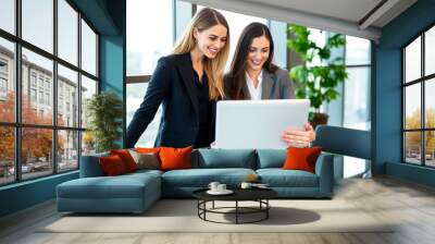 Two professional women collaborating happily over a laptop in a Wall mural