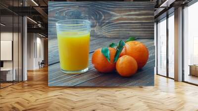 Fresh glass of orange juice, tangerines with leaves, close up Wall mural