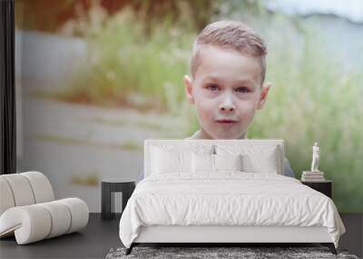 child boy 6 years old in a white T-shirt and fashionable hairstyle on the street in summer Wall mural