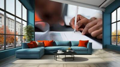 Close-up of the hands of an African American woman signing the company's annual income statement. Business concept, finance, income of a large company Wall mural