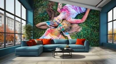 girls celebrate Indian holi festival with colorful paint powder on faces and body Wall mural