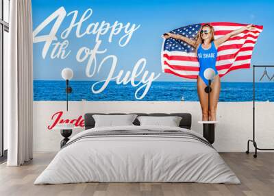 Beautiful cheerful woman holding an American flag on the beach. Wall mural