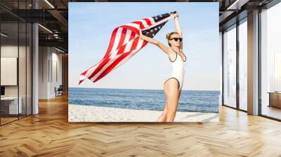 Beautiful patriotic woman holding an American flag on the beach.  USA Independence day, 4th July. Wall mural