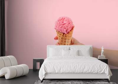 Hand holding strawberry ice cream cone on white background Wall mural