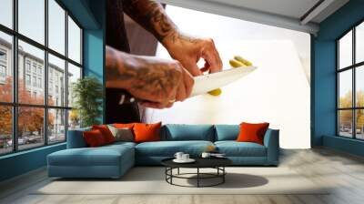 Tattooed chef cutting marinated cucumber on board in cafe  Wall mural