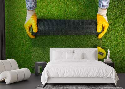 Men's hands hold a roll of artificial grass. Artificial turf background. Wall mural