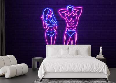 Neon sexy woman and man with a beautiful pumped-up body in blue and pink on a brick wall background. Wall mural