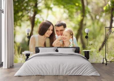 Happy mother, father and daughter playing in the park Wall mural