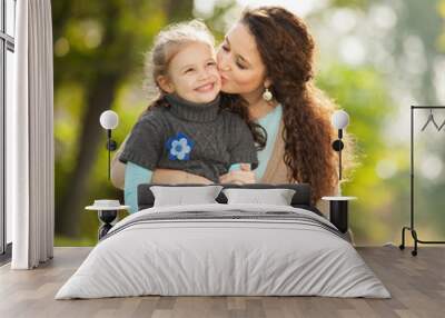 Mother kissing her daughter in the park Wall mural