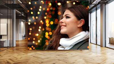 A girl with a hearing aid. The girl assumes hearing aid.Happy girl that hears well again. Holiday Concept. Decorating Christmas Tree. Beautiful  woman on christmas background. Wall mural