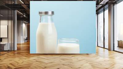 A bottle of milk and glass of milk on a basket on a blue backgro Wall mural