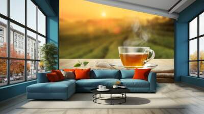 Cup of hot tea and tea leaf on the wooden table and the tea plantations background Wall mural