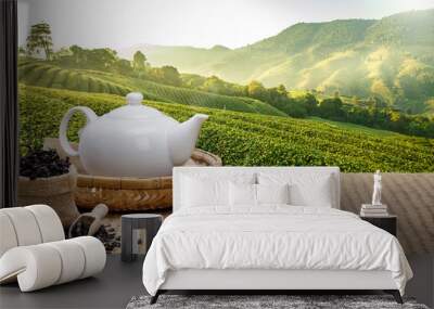 Warm cup of tea with teapot, green tea leaves and dried herbs on the bamboo mat at morning in plantations background with empty space, Organic product from the nature for healthy with traditional Wall mural