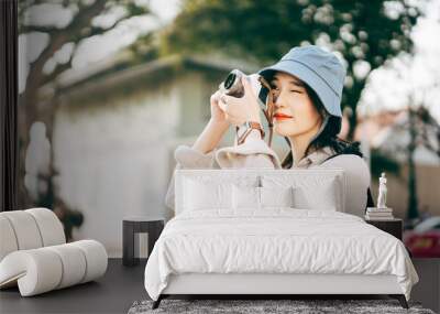 Attractive young adult asian woman traveller using camera for photo journey. Wall mural