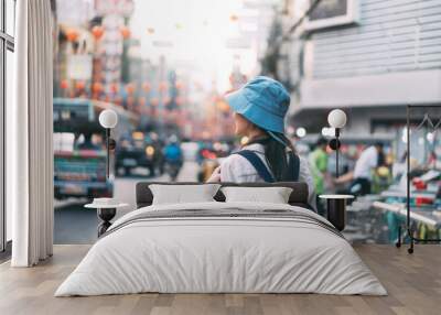 Rear view of walking young adult asian woman traveller backpack in city at street night market. Wall mural