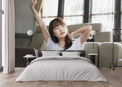 Relax asian teenager woman stretching arms after study online at home Wall mural