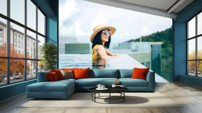 Summer travel asian tourist woman relax at outdoor luxury pool resort Wall mural