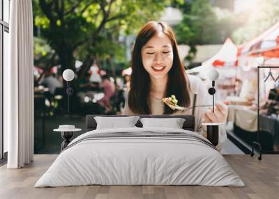 Young adult asian woman eat lunch food at restaurant outdoor on weekend day Wall mural