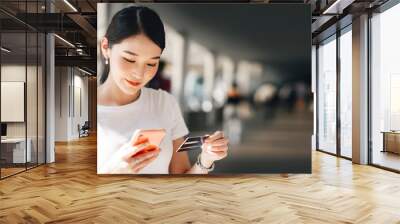 Young adult business asian woman consumer using creadit card and smartphone for shopping online. Wall mural