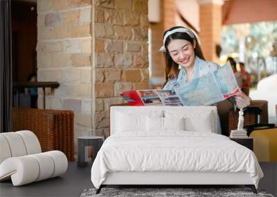 Young asian woman relax on sofa reading a map at lobby hotel. Wall mural