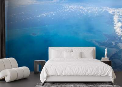 Aerial view of blue ocean and coast land with a few clouds Wall mural