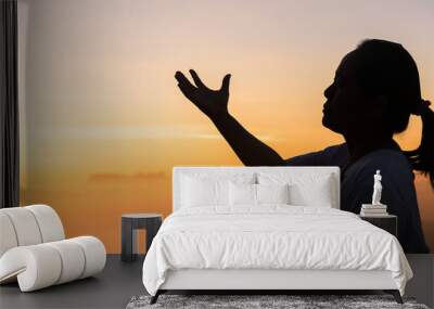 Faith of christian concept: Spiritual prayer hands over sunshine with blurred beautiful sunrise or sunset background. Christians who have believe, faith in God morning prayer. Wall mural